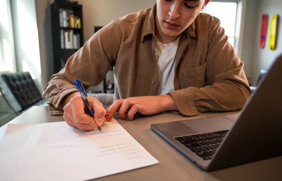 Persona tomando notas junto a un portátil mientras sigue una lección del curso
