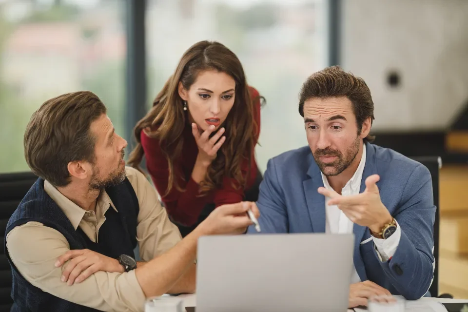 Un equipo trabaja alrededor de un portátil en una reunión