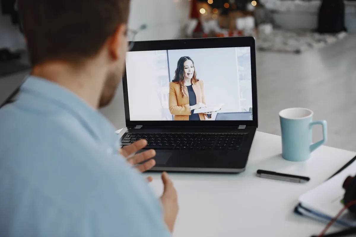 Una persona en una videollamada desde casa, con el portátil sobre la mesa