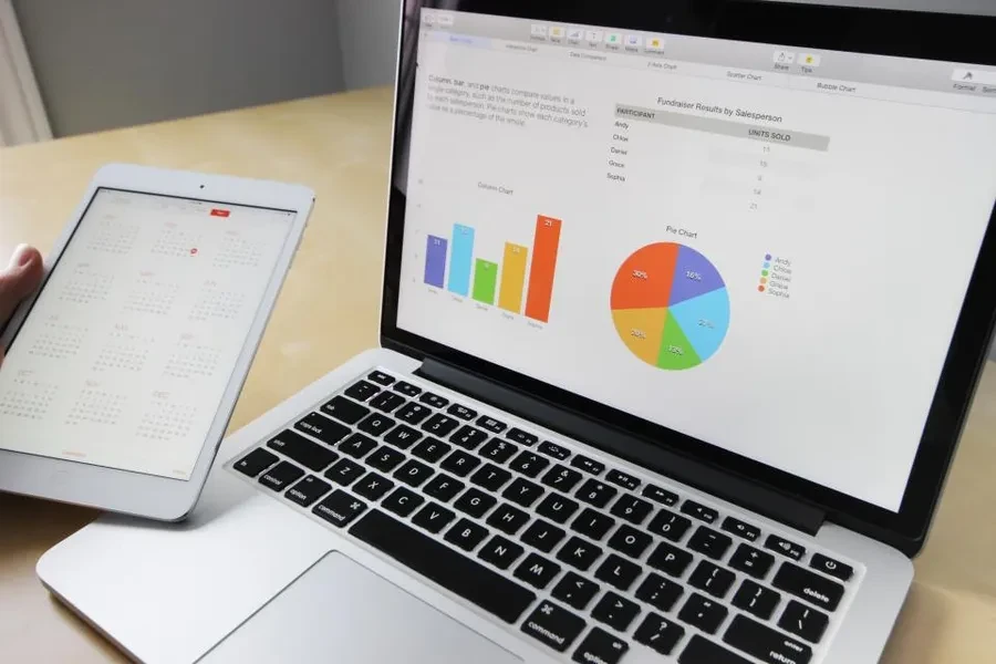 Portátil mostrando un panel de datos con gráficas sobre una mesa de trabajo
