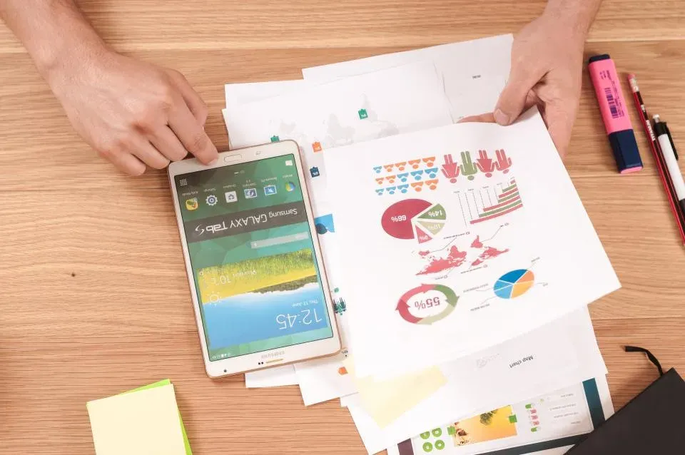 Gráficos y datos sobre una mesa de trabajo junto a una tableta
