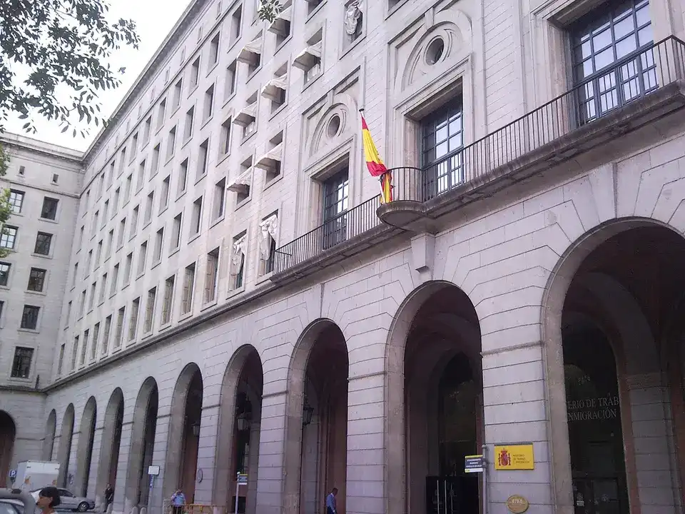 Fachada de piedra con arcos del edificio del Ministerio de Trabajo en Madrid, con la bandera de España