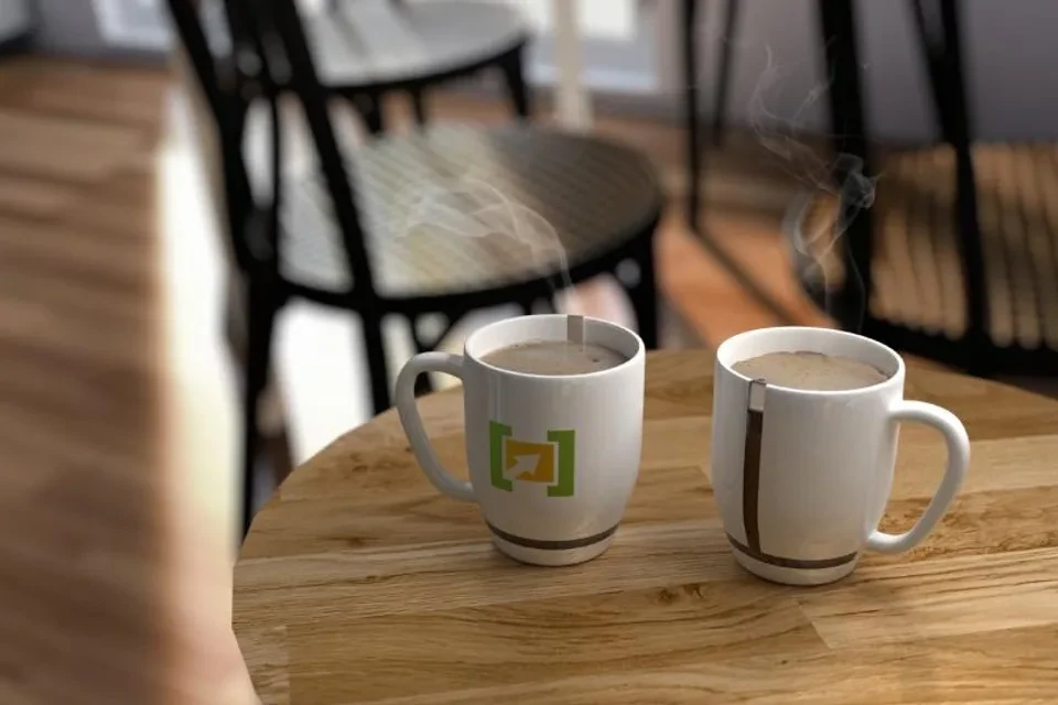 Dos tazas de café humeantes sobre una mesa de madera en una cafetería